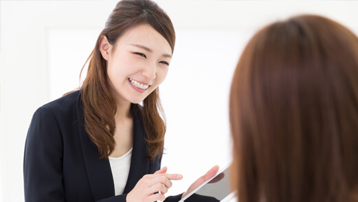 Smiling Asian woman with tablet speaking to another woman