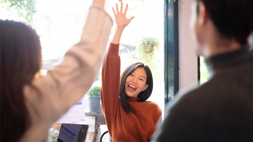 Smiling Asian woman with couple, both women celebrating with arm in the air